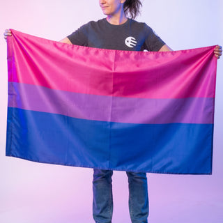 Person holding a bisexual pride flag against a studio background. Background bisexual lighting