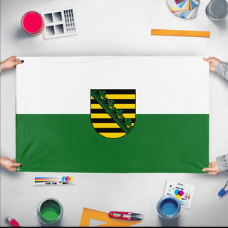 A mockup of the custom flag 'saxony flag' held up on a table during print checking