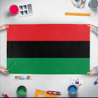 A mockup of the custom flag 'Pan-African Flag' held up on a table during print checking