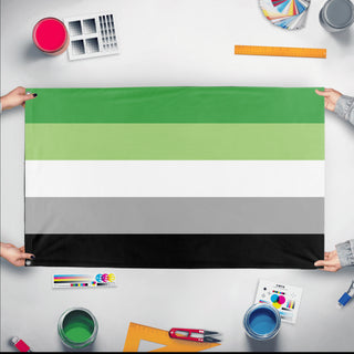 A mockup of the custom flag 'Aromantic Flag' held up on a table during print checking