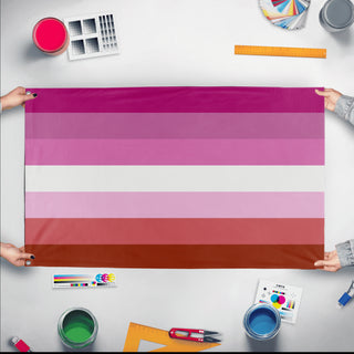 A mockup of the custom flag 'pink lesbian flag' held up on a table during print checking