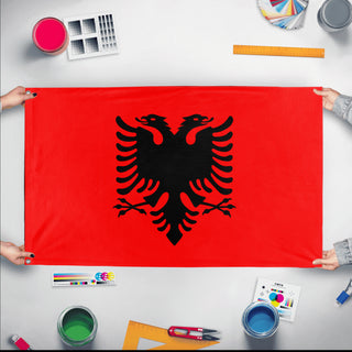 A mockup of the custom flag 'Flag of Albania flag' held up on a table during print checking