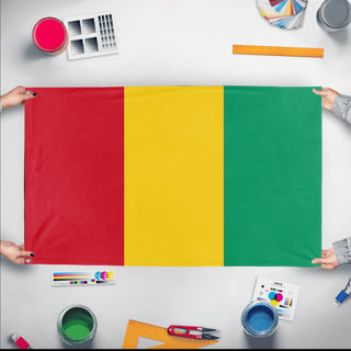 A mockup of the custom flag 'Flag of Guinea flag' held up on a table during print checking