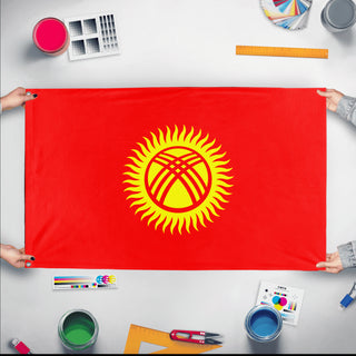 A mockup of the custom flag 'Flag of Kyrgyzstan flag' held up on a table during print checking