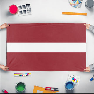 A mockup of the custom flag 'Flag of Latvia flag' held up on a table during print checking