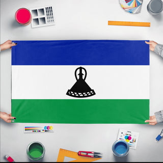 A mockup of the custom flag 'Flag of Lesotho flag' held up on a table during print checking