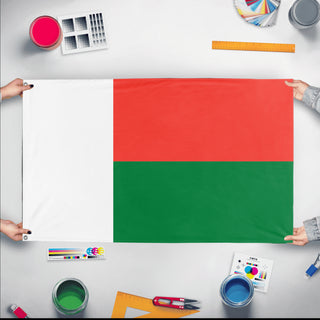 A mockup of the custom flag 'Flag of Madagascar flag' held up on a table during print checking
