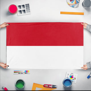 A mockup of the custom flag 'Flag of Monaco flag' held up on a table during print checking