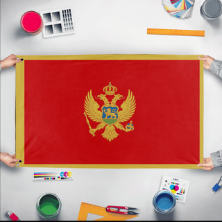 A mockup of the custom flag 'Flag of Montenegro flag' held up on a table during print checking