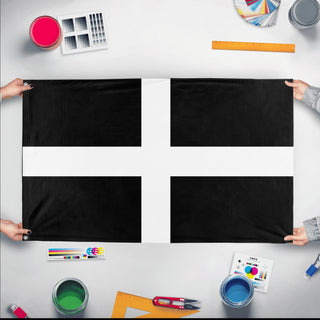 A mockup of the custom flag 'Cornwall Flag' held up on a table during print checking