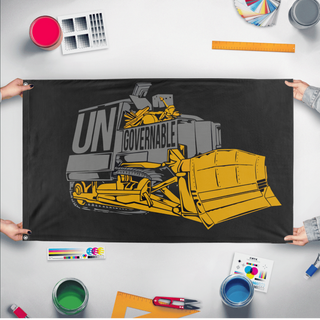 A mockup of the custom flag 'Killdozer Become Ungovernable Flag' held up on a table during print checking