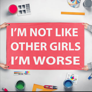 A mockup of the custom flag 'Not Like Other Girls Flag' held up on a table during print checking