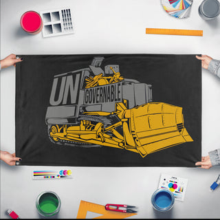 A mockup of the custom flag 'Killdozer Become Ungovernable Flag' held up on a table during print checking