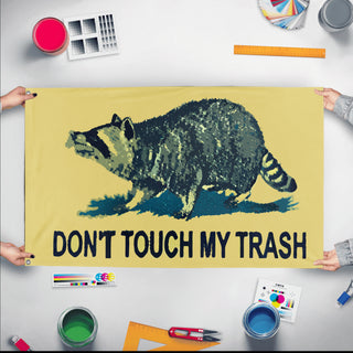 A mockup of the custom flag 'Don't Touch My Trash Flag' held up on a table during print checking