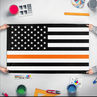 A mockup of the custom flag 'Thin Orange Line Flag' held up on a table during print checking