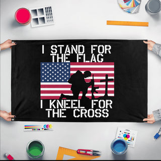 A mockup of the custom flag 'Stand For The Flag, Kneel For The Cross Flag' held up on a table during print checking