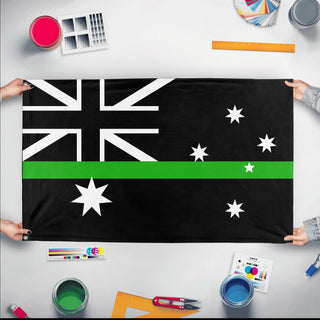 A mockup of the custom flag 'Thin Green Line Australia Flag' held up on a table during print checking