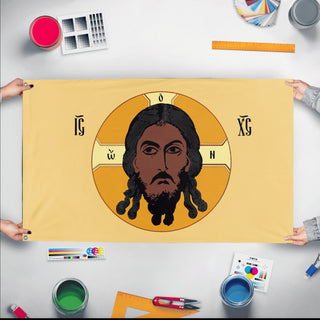 A mockup of the custom flag 'Holy Face of Christ Flag - Yellow flag' held up on a table during print checking