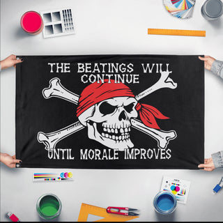 A mockup of the custom flag 'The Beatings Will Continue Until Morale Improves Flag' held up on a table during print checking