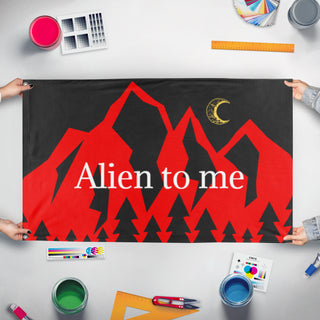 A mockup of the custom flag 'Alien to Me  flag' held up on a table during print checking