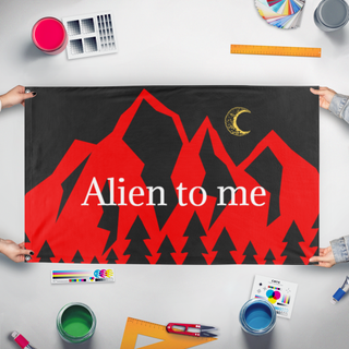 A mockup of the custom flag 'Alien to Me  flag' held up on a table during print checking