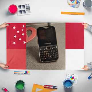 A mockup of the custom flag 'T flag' held up on a table during print checking