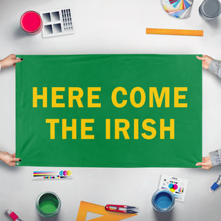 A mockup of the custom flag 'Here Come the Irish flag' held up on a table during print checking