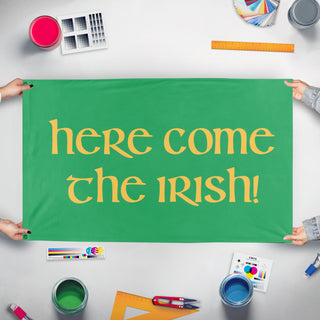 A mockup of the custom flag 'Here Come The Irish flag' held up on a table during print checking