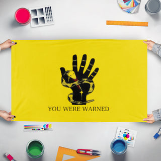 A mockup of the custom flag 'You were warned flag' held up on a table during print checking