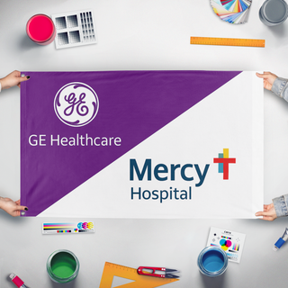 A mockup of the custom flag 'GE/Mercy  flag' held up on a table during print checking