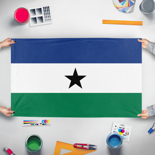 A mockup of the custom flag 'Anyguola flag' held up on a table during print checking