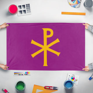 A mockup of the custom flag 'Purple Chi Ro flag' held up on a table during print checking