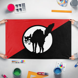 A mockup of the custom flag 'Sabot Cat flag' held up on a table during print checking