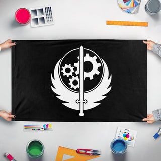 A mockup of the custom flag 'Black and White Brotherhood of Steel flag' held up on a table during print checking