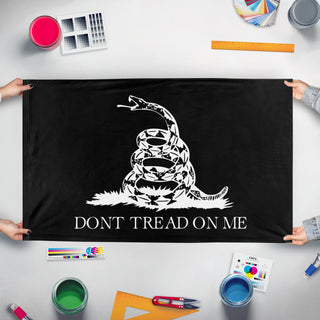 A mockup of the custom flag 'Black and White Gadsden flag' held up on a table during print checking