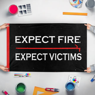 A mockup of the custom flag 'Expect Fire, Expect Victims flag' held up on a table during print checking