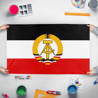 A mockup of the custom flag 'Democratic Republic of Germany' held up on a table during print checking