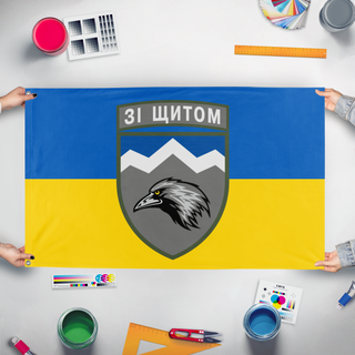 A mockup of the custom flag '109th mountain assault battalion flag' held up on a table during print checking