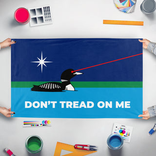 A mockup of the custom flag 'Don't Tread On Me Laser Loon flag' held up on a table during print checking