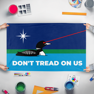 A mockup of the custom flag 'Laser Loon Don't Tread On Us flag' held up on a table during print checking