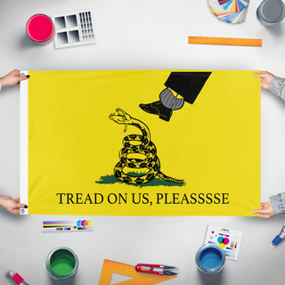 A mockup of the custom flag 'TREAD ON US, PLEASE flag' held up on a table during print checking