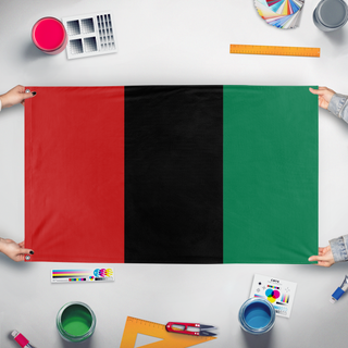 A mockup of the custom flag 'Red Black and Green Tricolor flag' held up on a table during print checking