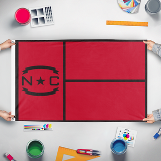 A mockup of the custom flag 'NC Canes flag' held up on a table during print checking