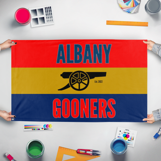 A mockup of the custom flag 'Gooners flag' held up on a table during print checking