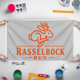 A mockup of the custom flag 'RasselbockRun flag' held up on a table during print checking