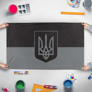 A mockup of the custom flag 'Darkmode Ukraine Coat of Arms flag' held up on a table during print checking