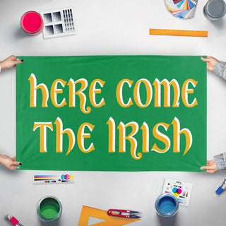 A mockup of the custom flag 'Here Come The Irish flag' held up on a table during print checking