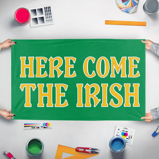 A mockup of the custom flag 'Here Come the Irish flag' held up on a table during print checking
