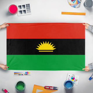 A mockup of the custom flag 'Igbo people of Nigeria Flag' held up on a table during print checking