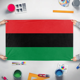 A mockup of the custom flag 'Pan-African Flag' held up on a table during print checking